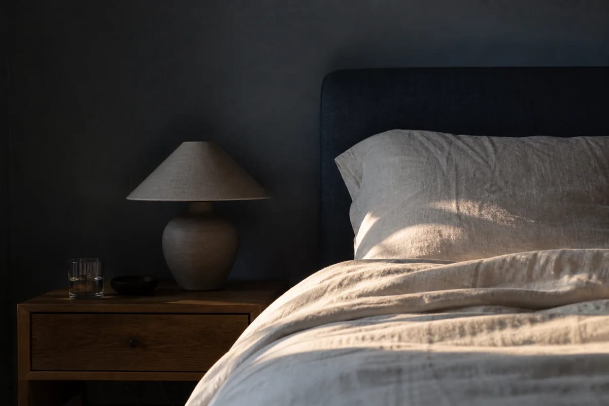 A simple bedside scene suggesting good sleep: a dark, cool room, calm and restorative, no people in view
